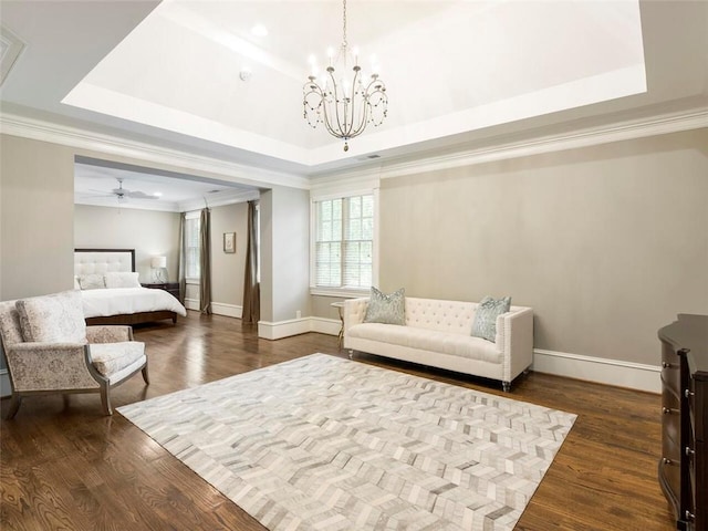 living room featuring dark wood-type flooring, crown molding, a tray ceiling, and ceiling fan with notable chandelier