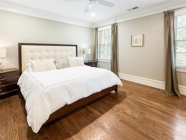 bedroom with multiple windows, dark hardwood / wood-style floors, ceiling fan, and ornamental molding