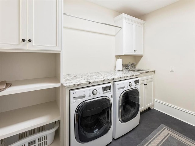 washroom with sink, cabinets, dark tile flooring, and independent washer and dryer