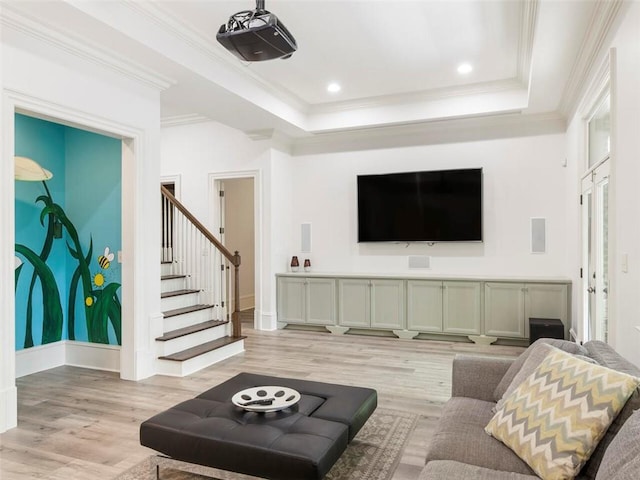 living room featuring ornamental molding, a tray ceiling, and light wood-type flooring