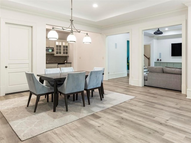 dining room featuring a tray ceiling, crown molding, a chandelier, and light hardwood / wood-style floors