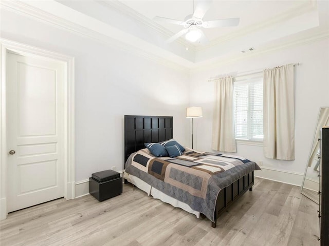 bedroom featuring light hardwood / wood-style flooring, ceiling fan, a raised ceiling, and crown molding