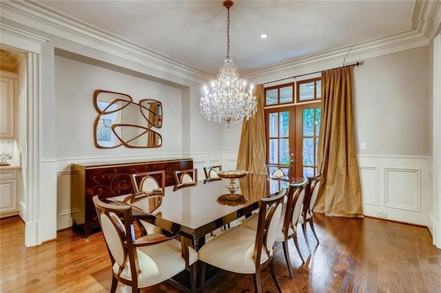 dining room featuring french doors, an inviting chandelier, ornamental molding, and light hardwood / wood-style flooring