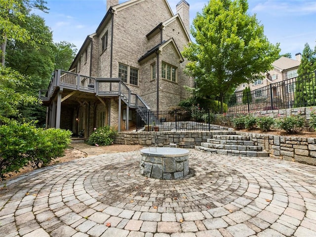 exterior space featuring a wooden deck, a fire pit, and a patio area