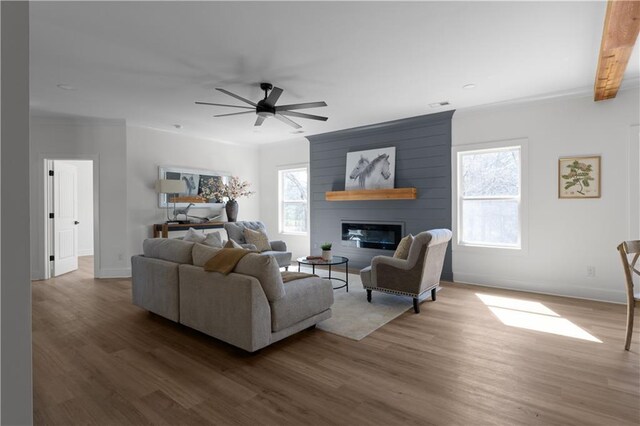 living area featuring a ceiling fan, visible vents, wood finished floors, baseboards, and a fireplace