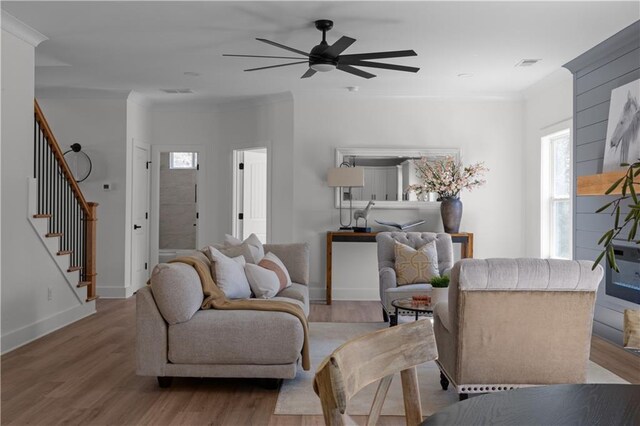 living area with stairway, a ceiling fan, crown molding, and visible vents
