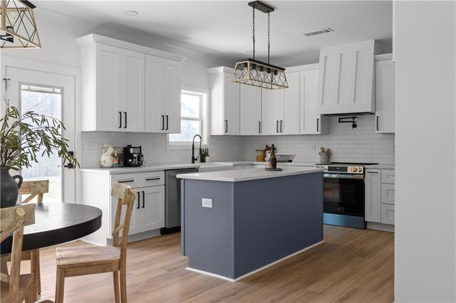 kitchen featuring a sink, light wood-style floors, appliances with stainless steel finishes, and light countertops
