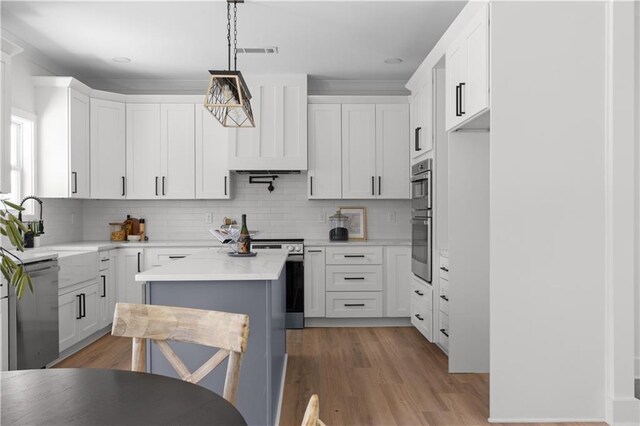 kitchen with visible vents, white cabinets, light wood-style floors, appliances with stainless steel finishes, and a center island