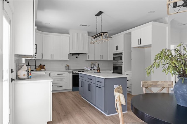kitchen with a sink, appliances with stainless steel finishes, premium range hood, and light countertops