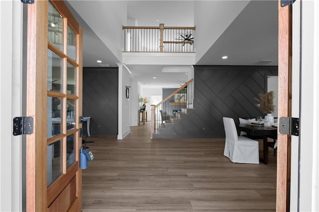 entrance foyer featuring wood finished floors, stairs, a high ceiling, wood walls, and an accent wall