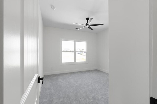 carpeted spare room with ceiling fan and baseboards