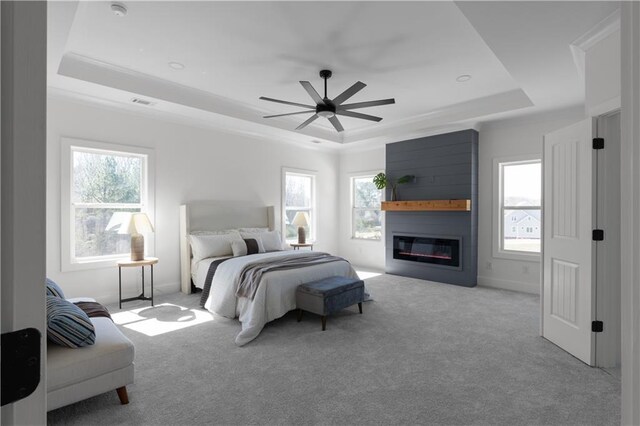 carpeted bedroom featuring a fireplace, a raised ceiling, and ceiling fan