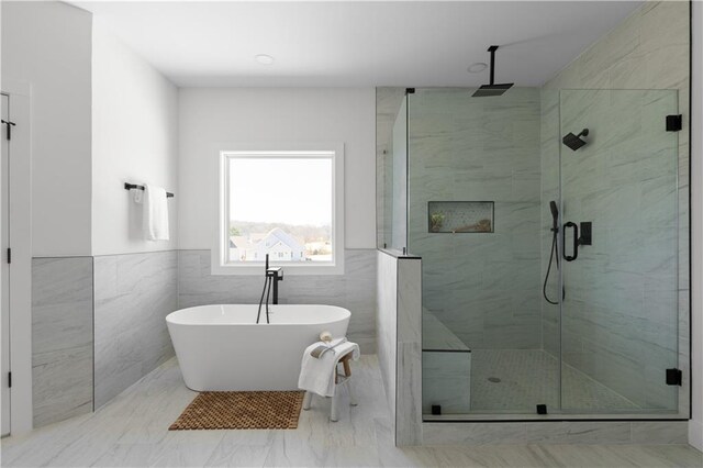 bathroom with tile walls, a freestanding tub, and a stall shower
