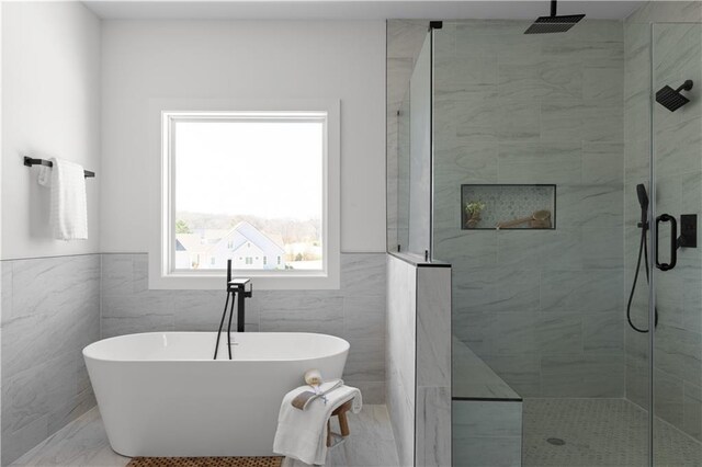 bathroom featuring a tile shower, a wainscoted wall, a freestanding bath, and tile walls