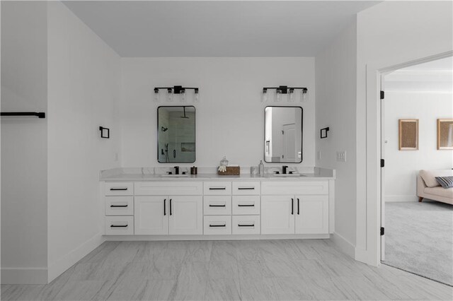 ensuite bathroom with double vanity, baseboards, marble finish floor, and a sink