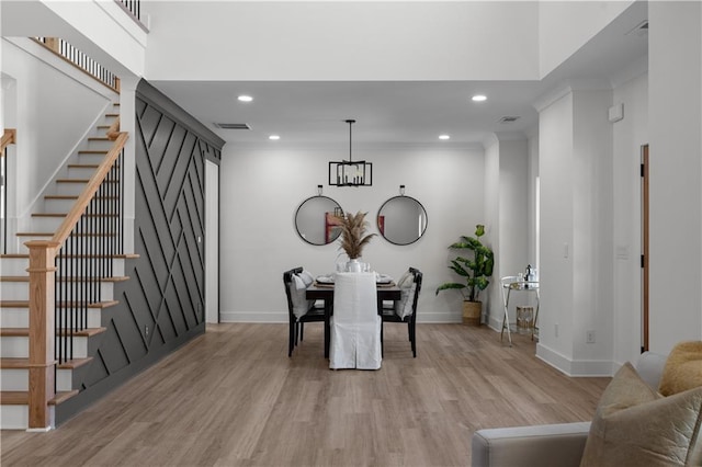 dining area with light wood-type flooring, visible vents, baseboards, and stairs