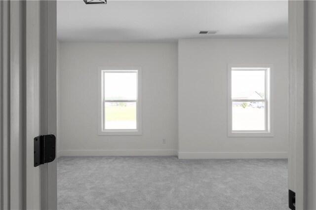 carpeted empty room featuring visible vents, a healthy amount of sunlight, and baseboards