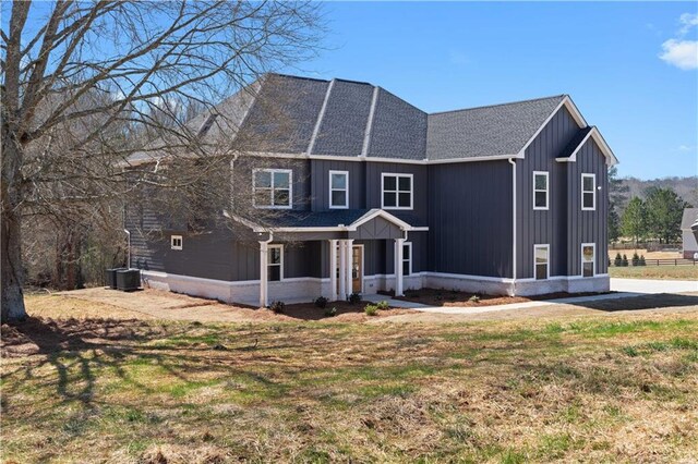 view of front of property featuring cooling unit, board and batten siding, and a front lawn