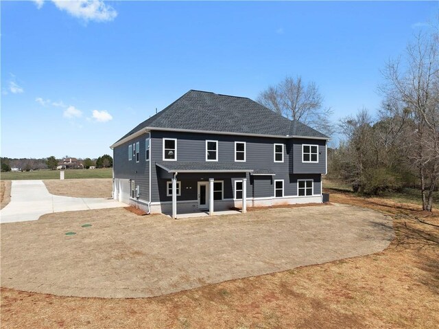back of property with an attached garage, driveway, and roof with shingles