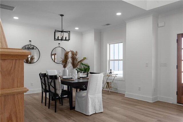 dining space featuring visible vents, light wood-style floors, crown molding, baseboards, and a chandelier