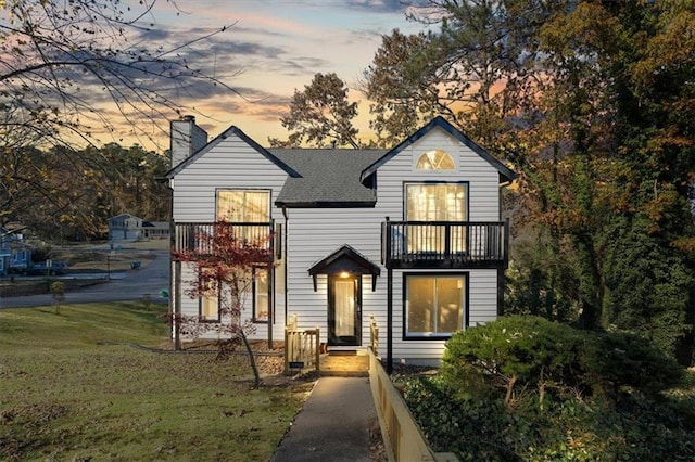 view of front of home featuring a balcony and a yard