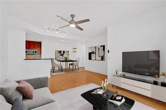 dining space with ceiling fan, sink, light hardwood / wood-style floors, and rail lighting