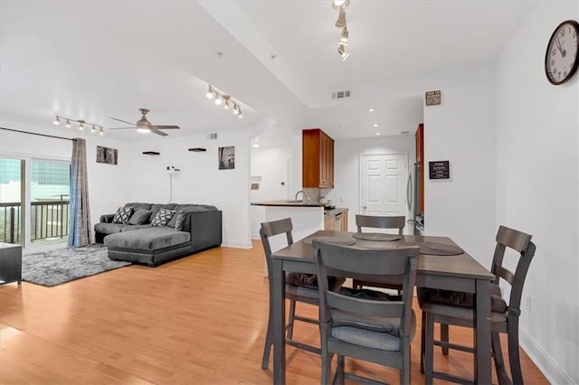 dining room featuring track lighting, light wood-style flooring, visible vents, and ceiling fan