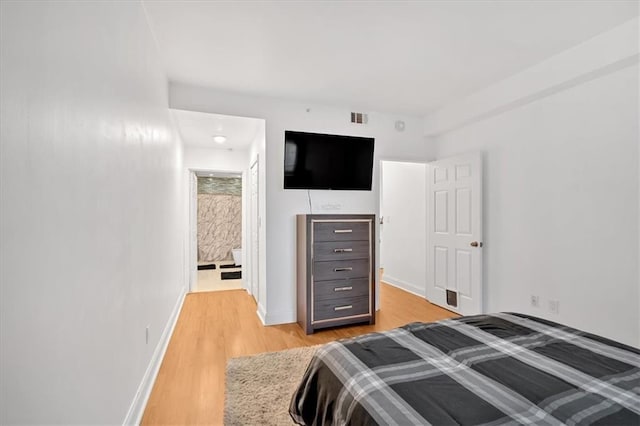 bedroom featuring ensuite bathroom and light wood-type flooring