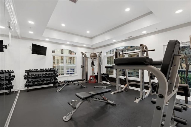 exercise room with ornamental molding and a tray ceiling