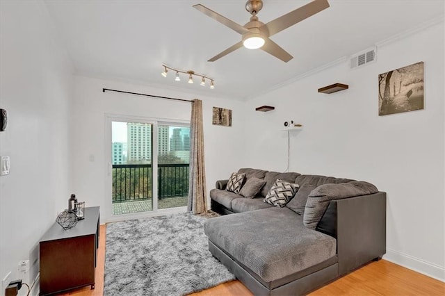 living room featuring hardwood / wood-style flooring, crown molding, and ceiling fan