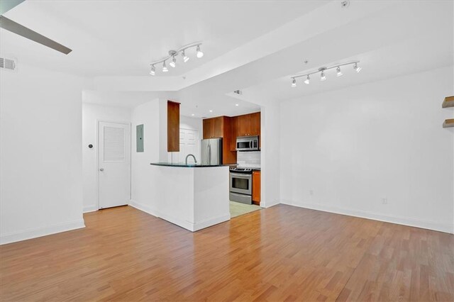 kitchen featuring sink, stainless steel appliances, kitchen peninsula, and dark stone counters