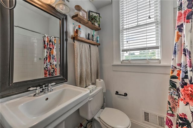 bathroom featuring curtained shower, toilet, and sink