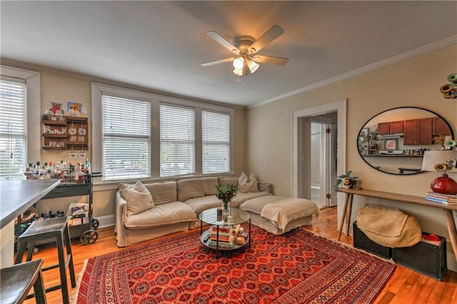 living room with ornamental molding, light hardwood / wood-style floors, and ceiling fan