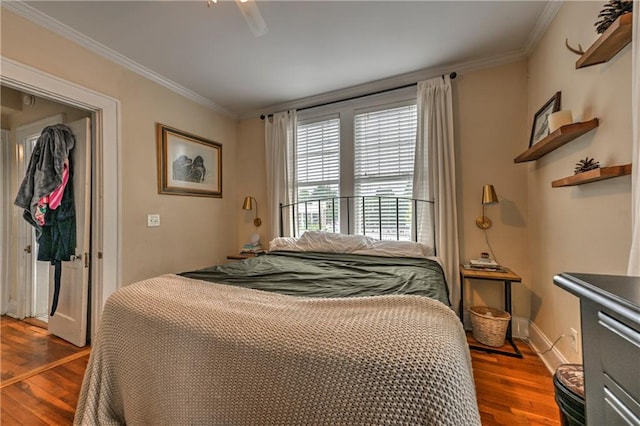 bedroom with crown molding, dark wood-type flooring, and ceiling fan