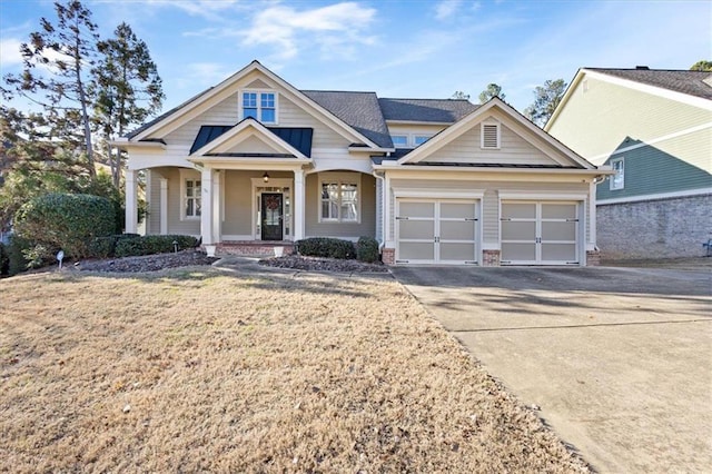 view of front of home featuring a front yard, a porch, and a garage