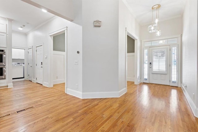 entryway featuring ornamental molding, light hardwood / wood-style floors, and washer / dryer