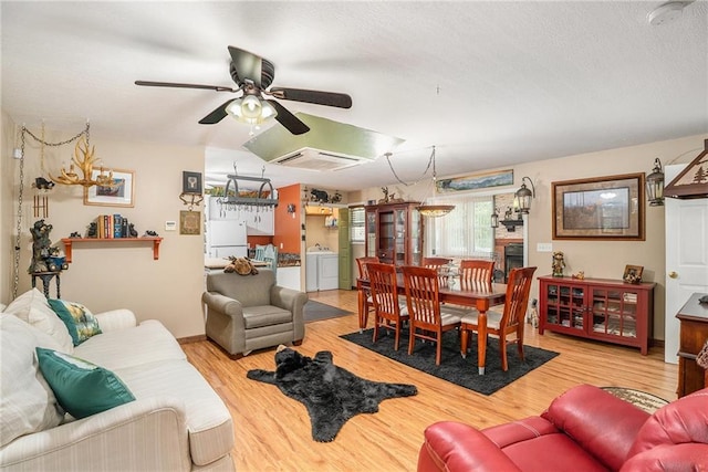 living room featuring light hardwood / wood-style flooring, washer and dryer, and ceiling fan