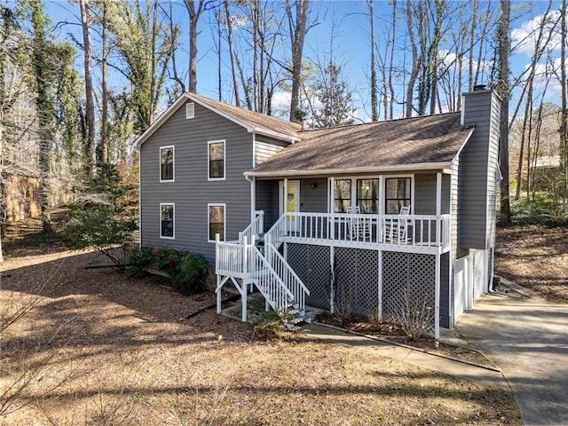 tri-level home with driveway, stairway, covered porch, an attached garage, and a chimney