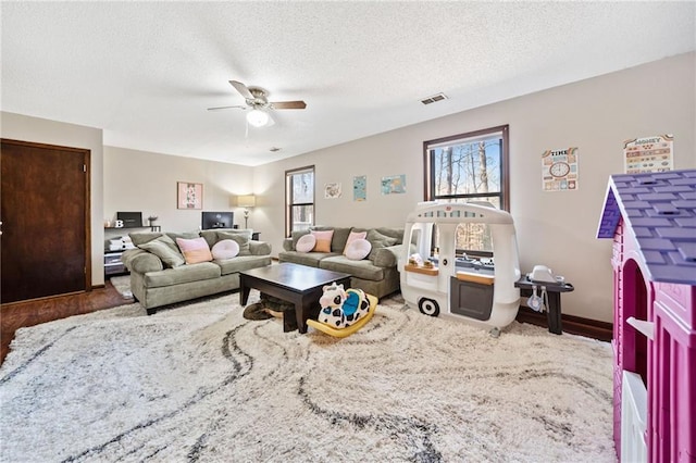 living area featuring visible vents, a textured ceiling, a ceiling fan, and wood finished floors