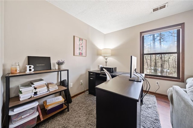 home office with wood finished floors, baseboards, visible vents, and a textured ceiling