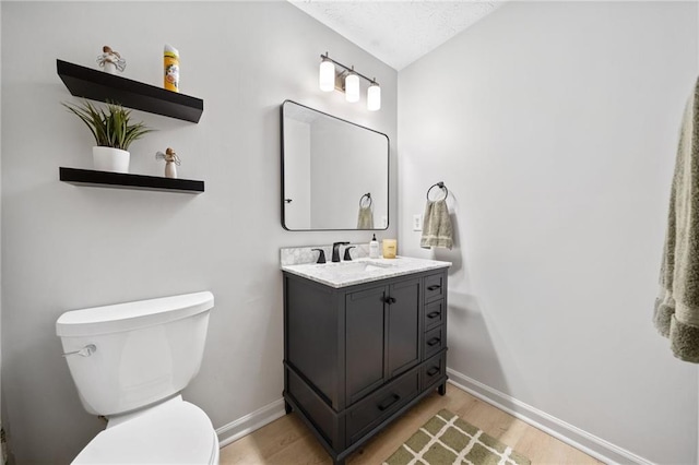 bathroom featuring toilet, vanity, baseboards, and wood finished floors