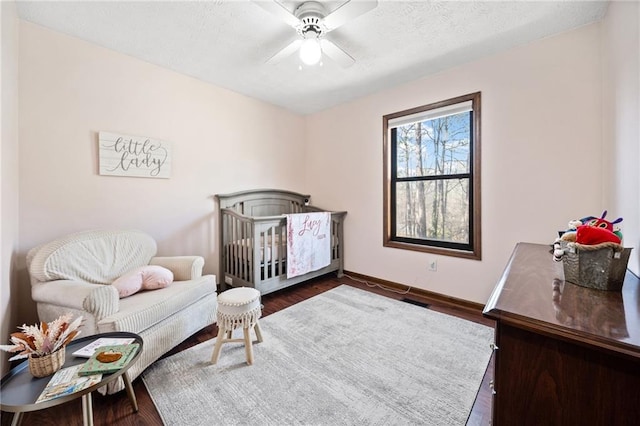 bedroom featuring baseboards, a textured ceiling, dark wood-style floors, and a ceiling fan