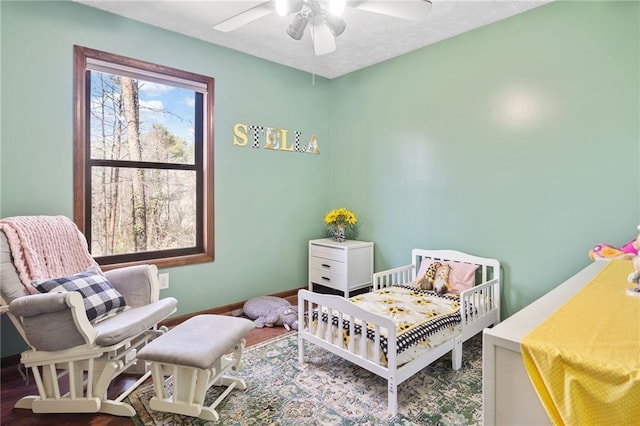 bedroom with a ceiling fan, wood finished floors, baseboards, and a textured ceiling