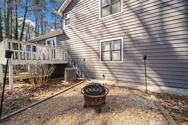 view of side of property with stairway, central air condition unit, a fire pit, and a wooden deck