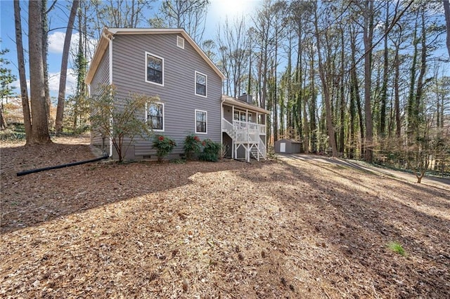 rear view of property with crawl space, a shed, stairway, and an outdoor structure