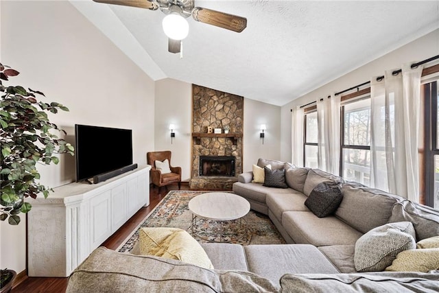 living area featuring a textured ceiling, dark wood-style floors, a fireplace, lofted ceiling, and ceiling fan