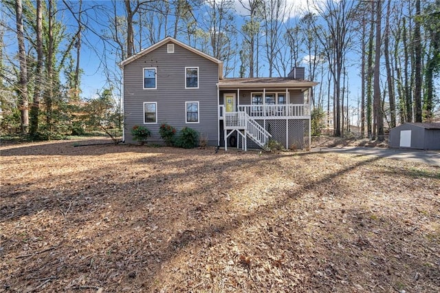 back of property with stairs, an outbuilding, a porch, and a chimney