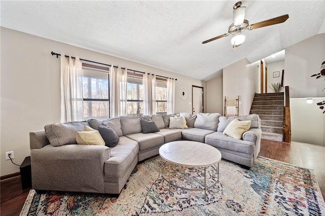 living area featuring vaulted ceiling, a textured ceiling, a ceiling fan, and wood finished floors