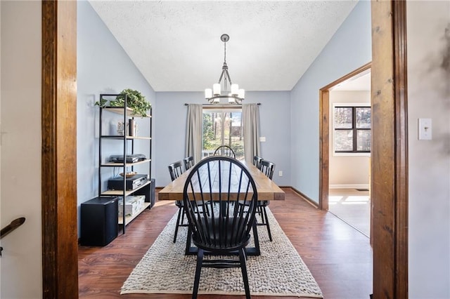 dining room featuring baseboards, a chandelier, dark wood finished floors, lofted ceiling, and a textured ceiling