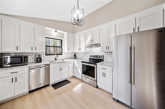 kitchen with white cabinetry, under cabinet range hood, appliances with stainless steel finishes, and a sink